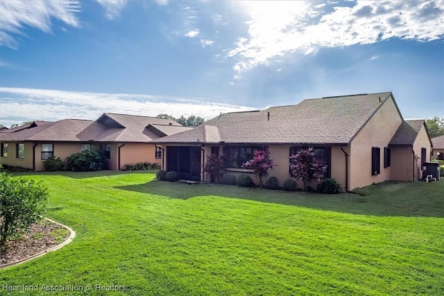 rear view of property with stucco siding, a lawn, central AC, and a sunroom