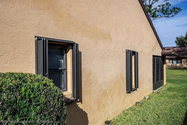 view of side of property featuring stucco siding and a lawn