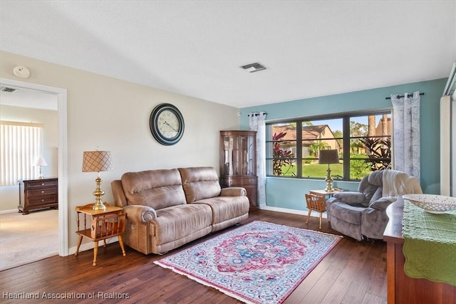 living room featuring visible vents, baseboards, and hardwood / wood-style floors