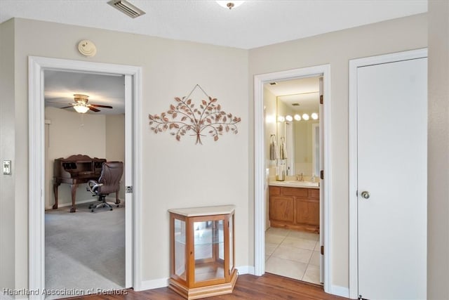 hall with baseboards, visible vents, and a sink