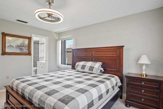 bedroom with visible vents, light colored carpet, baseboards, and connected bathroom