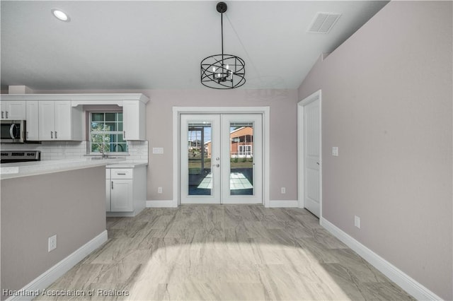 kitchen featuring white cabinetry, stainless steel appliances, tasteful backsplash, a healthy amount of sunlight, and french doors