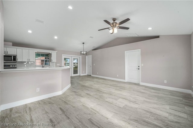 kitchen featuring lofted ceiling, tasteful backsplash, pendant lighting, ceiling fan, and white cabinets