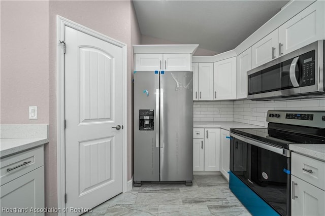 kitchen with white cabinetry, decorative backsplash, light stone countertops, and appliances with stainless steel finishes