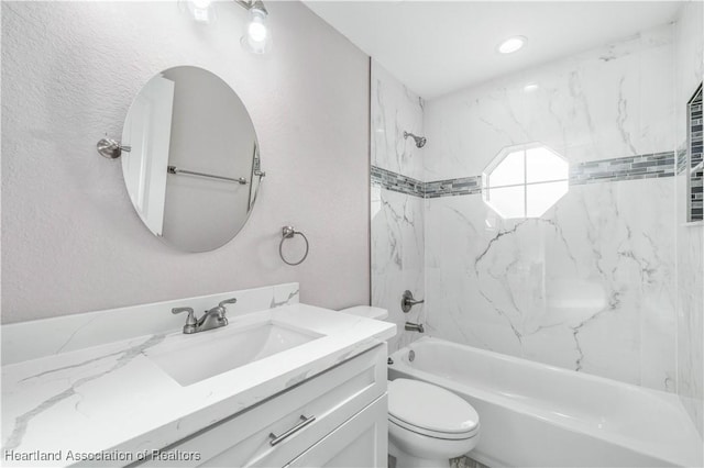 full bathroom featuring tiled shower / bath, vanity, and toilet