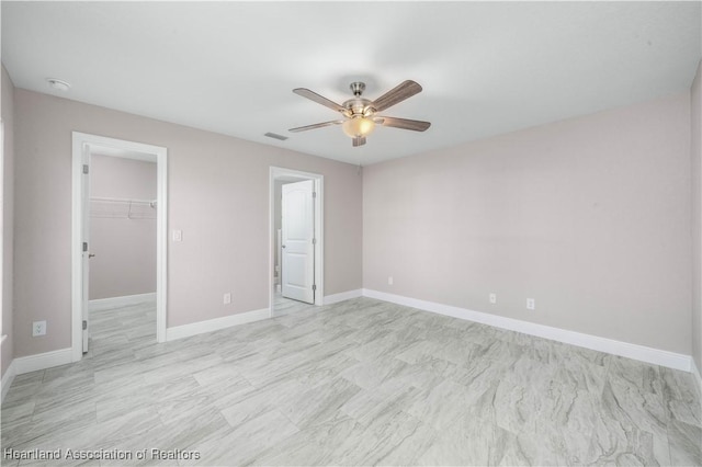 unfurnished bedroom featuring a walk in closet, ceiling fan, and a closet