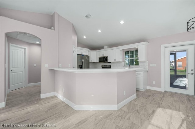 kitchen with white cabinetry, decorative backsplash, kitchen peninsula, and appliances with stainless steel finishes