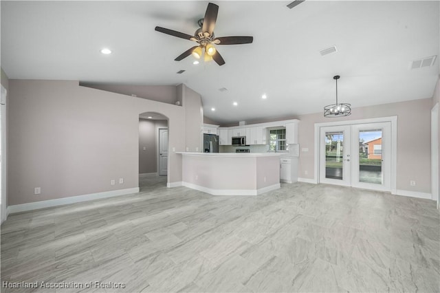 unfurnished living room featuring french doors, lofted ceiling, and ceiling fan with notable chandelier