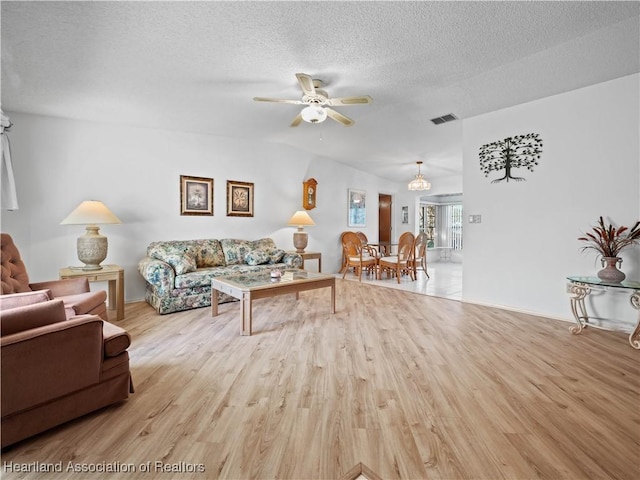 living room with ceiling fan, a textured ceiling, and light hardwood / wood-style flooring