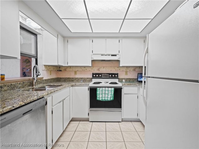 kitchen featuring light stone countertops, white appliances, sink, light tile patterned floors, and white cabinetry