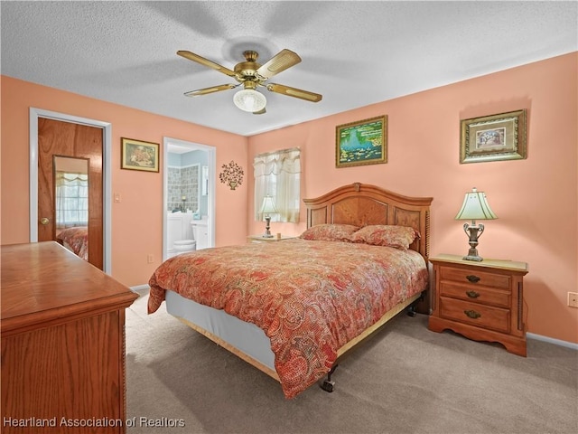 carpeted bedroom with ensuite bathroom, ceiling fan, and a textured ceiling