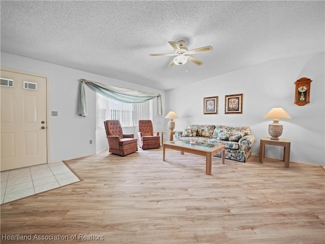 living room featuring ceiling fan, light hardwood / wood-style flooring, and a textured ceiling