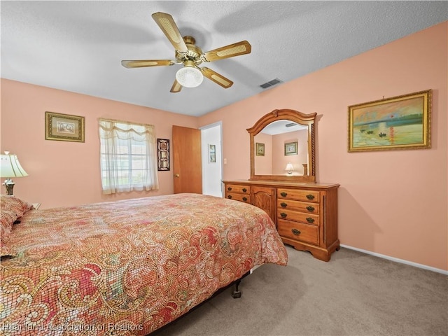 carpeted bedroom with ceiling fan and a textured ceiling