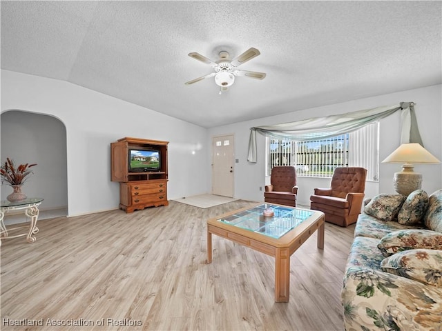 living room featuring ceiling fan, lofted ceiling, a textured ceiling, and light hardwood / wood-style flooring