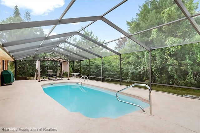 view of pool with glass enclosure, a grill, and a patio area