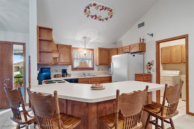 kitchen with pendant lighting, independent washer and dryer, light tile patterned floors, white fridge, and kitchen peninsula