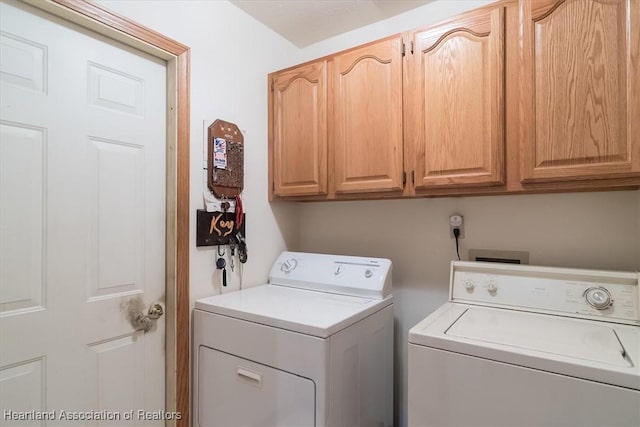 laundry room featuring washer and clothes dryer and cabinets