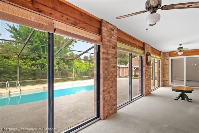 unfurnished sunroom with ceiling fan and a swimming pool