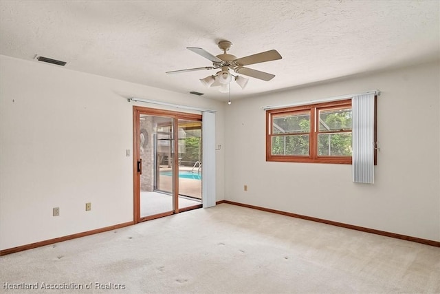 carpeted spare room with ceiling fan and a textured ceiling