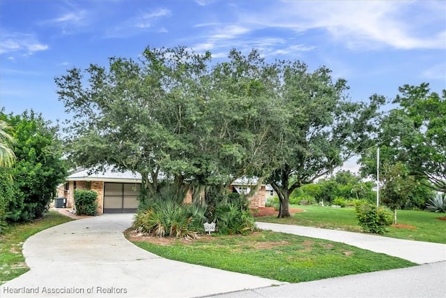 view of property hidden behind natural elements featuring a garage and a front lawn