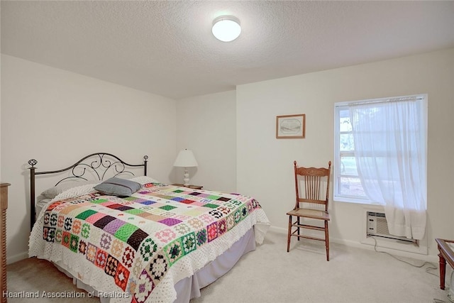 carpeted bedroom featuring baseboards, a textured ceiling, and an AC wall unit