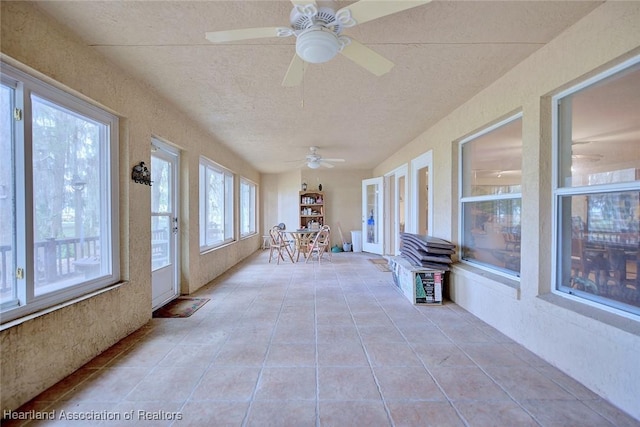 unfurnished sunroom with a ceiling fan