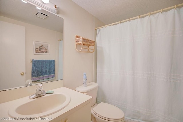 full bathroom featuring a textured ceiling, toilet, vanity, and visible vents