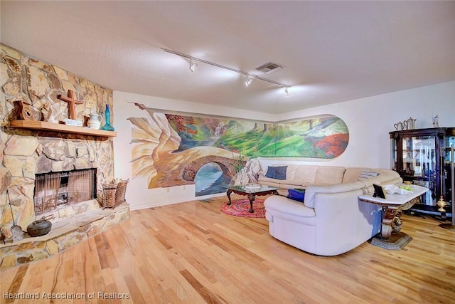 living room with visible vents, a fireplace, and wood finished floors
