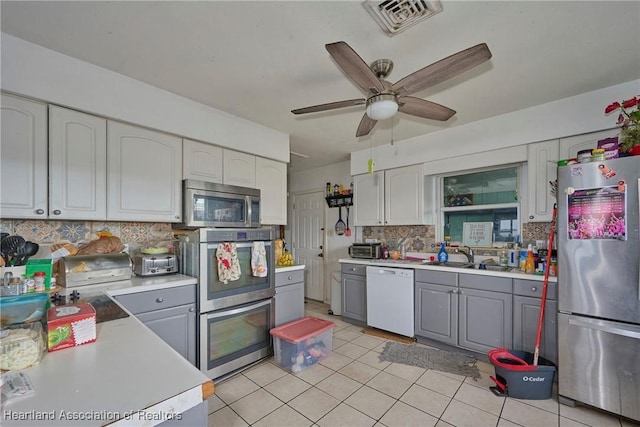 kitchen featuring stainless steel appliances, light countertops, a sink, and backsplash