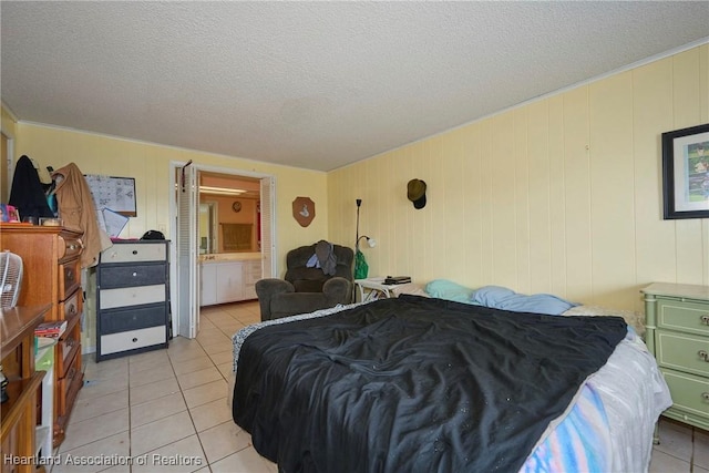bedroom featuring a textured ceiling, ensuite bathroom, and light tile patterned floors