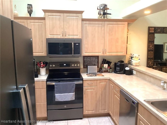 kitchen with stainless steel appliances, light brown cabinetry, and light tile patterned floors