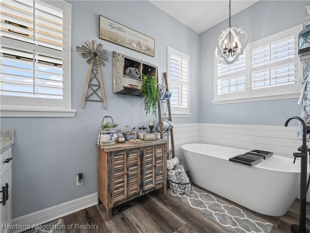 bathroom with vanity, a notable chandelier, a washtub, and hardwood / wood-style flooring