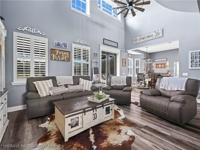 living room with ceiling fan, dark wood-type flooring, and a high ceiling