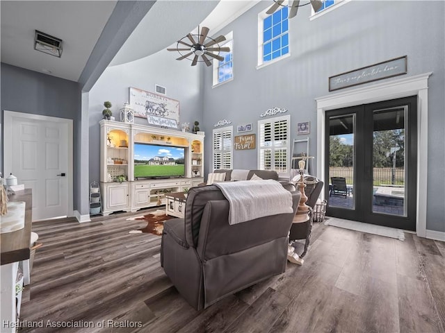 living room featuring ceiling fan, french doors, dark hardwood / wood-style floors, and a high ceiling