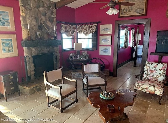 living room featuring ceiling fan, beam ceiling, and a stone fireplace