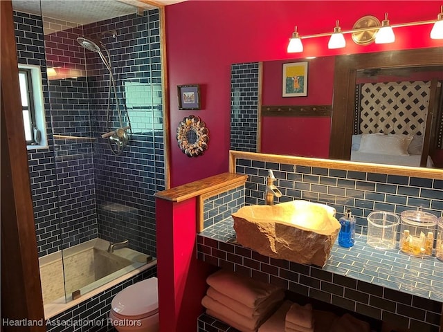 bathroom with toilet, tiled shower / bath, and backsplash