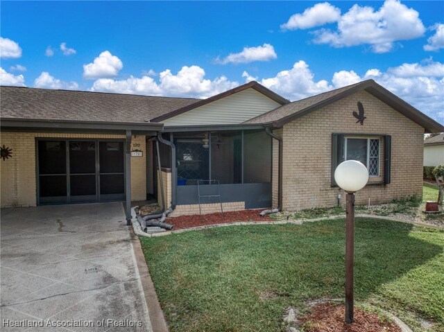 170 Parkview Cir, Lake Placid, FL 33852 - ranch-style house with brick siding, a front yard, and a sunroom