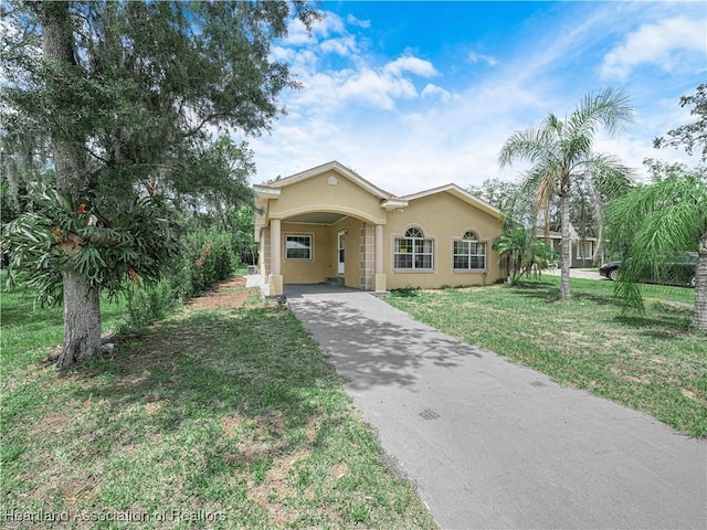 1621 Warfield Pl, Sebring, FL 33870 - view of front facade featuring stucco siding, asphalt driveway, a front lawn, and an attached carport