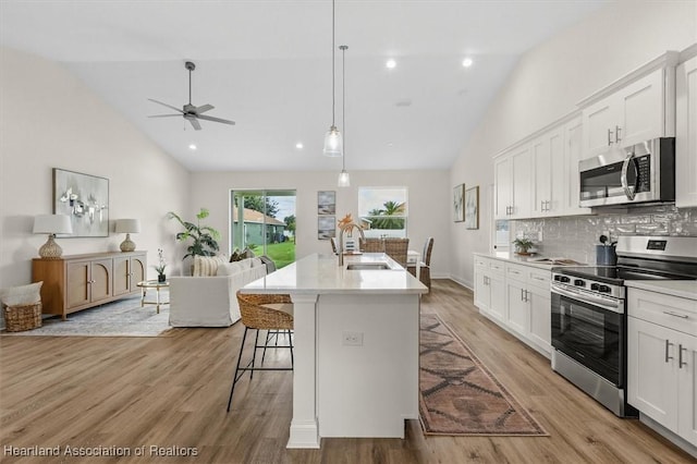 4954 San Ignacio Dr, Sebring, FL 33872 - kitchen featuring appliances with stainless steel finishes, open floor plan, a kitchen bar, a ceiling fan, and white cabinetry