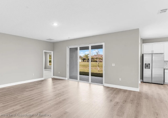 unfurnished living room with light hardwood / wood-style floors and a textured ceiling