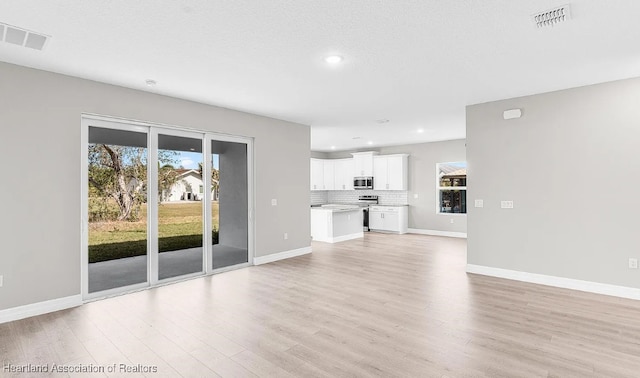 unfurnished living room with a textured ceiling and light wood-type flooring