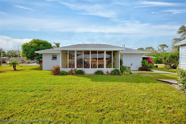 rear view of property featuring a sunroom and a yard