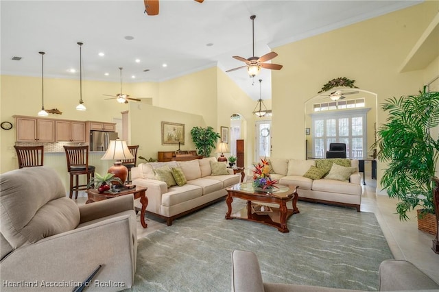 living room with ornamental molding, ceiling fan, and a high ceiling