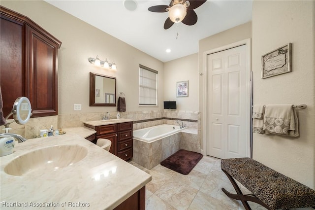 bathroom with vanity, a relaxing tiled tub, and ceiling fan