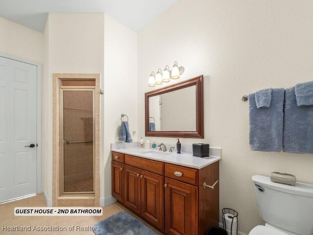 bathroom featuring tile patterned flooring, vanity, toilet, and walk in shower