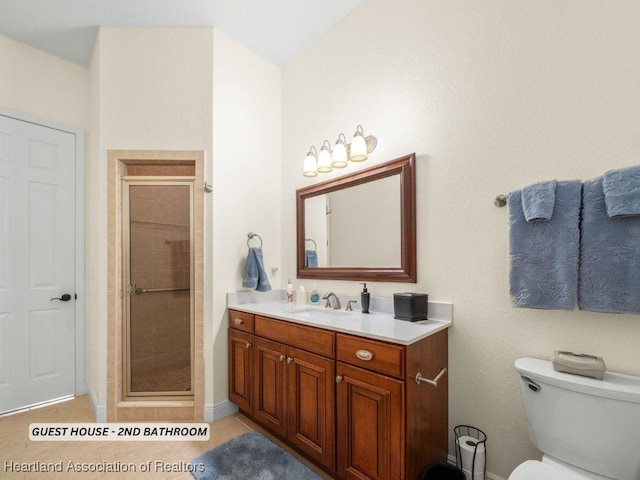 bathroom with tile patterned floors, toilet, vanity, and walk in shower