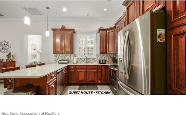 kitchen with kitchen peninsula, stainless steel appliances, sink, ornamental molding, and pendant lighting