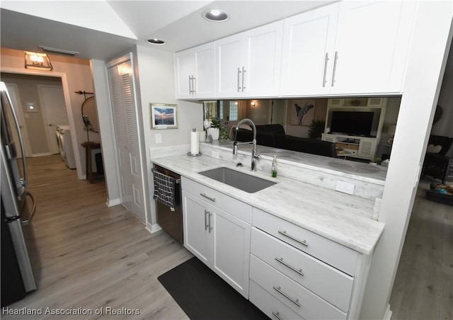 kitchen with dishwasher, light wood-type flooring, freestanding refrigerator, white cabinetry, and a sink