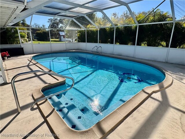 outdoor pool featuring glass enclosure and a patio area