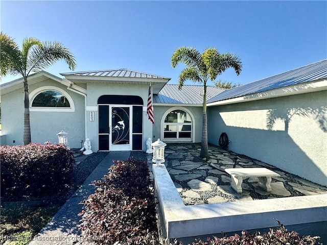 view of exterior entry with stucco siding and metal roof